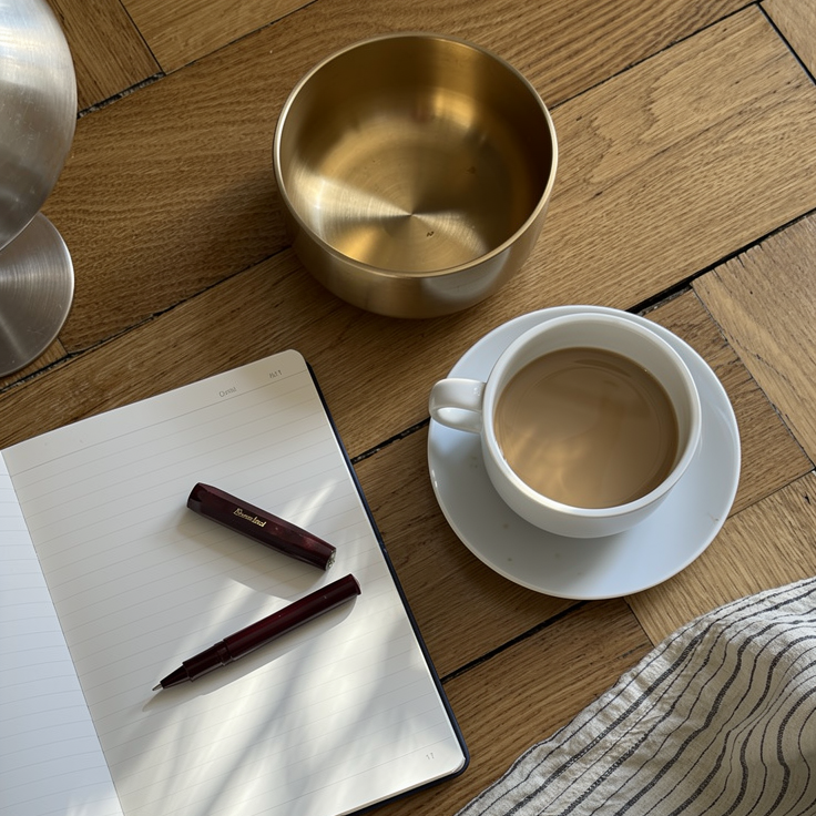 Morning reset — brass singing bowl beside coffee and an open notebook