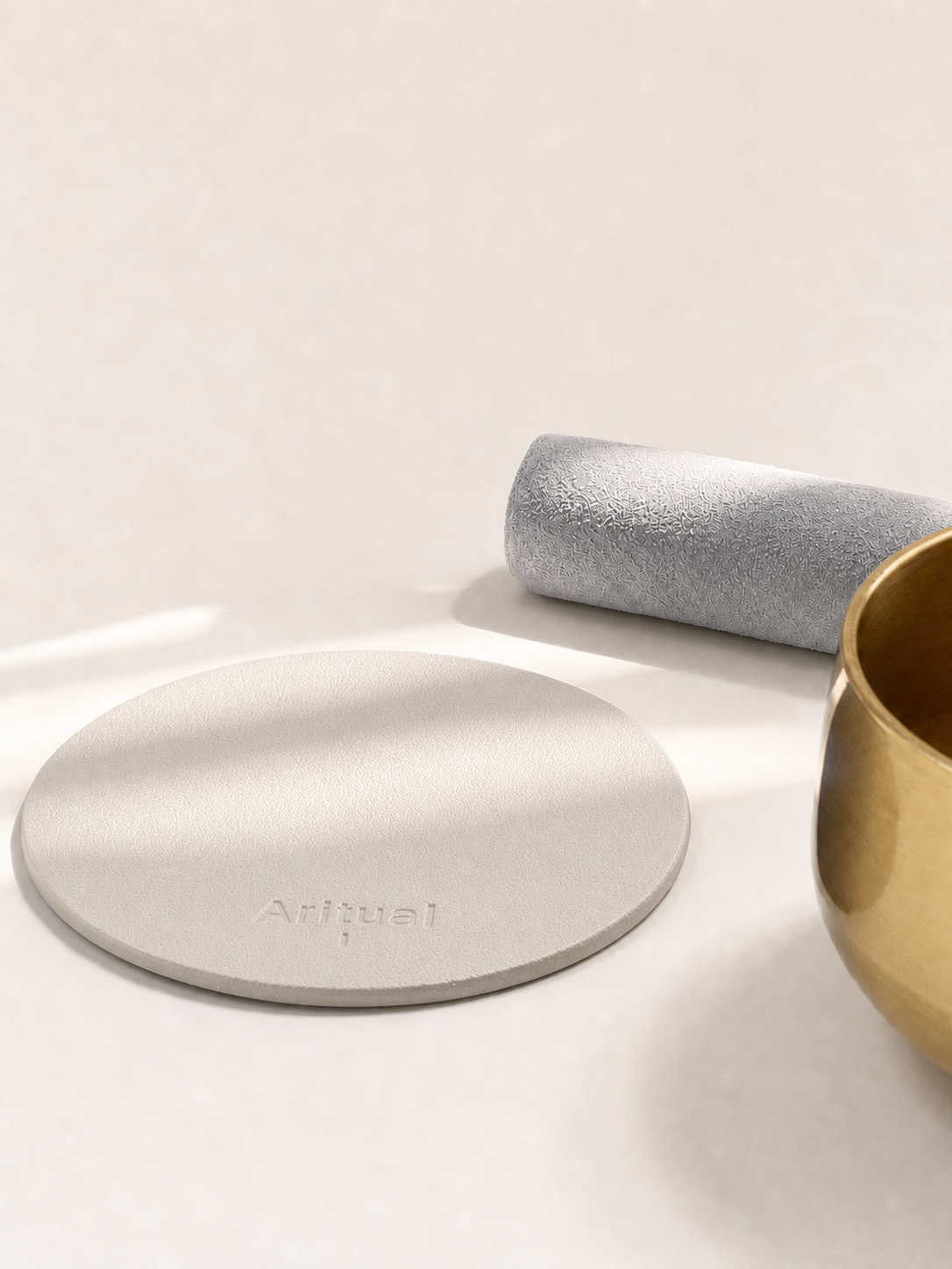 Ivory leather pad beside the brass singing bowl and suede mallet