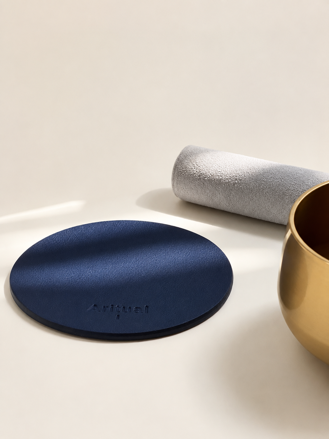 Navy blue leather pad beside the brass singing bowl and suede mallet