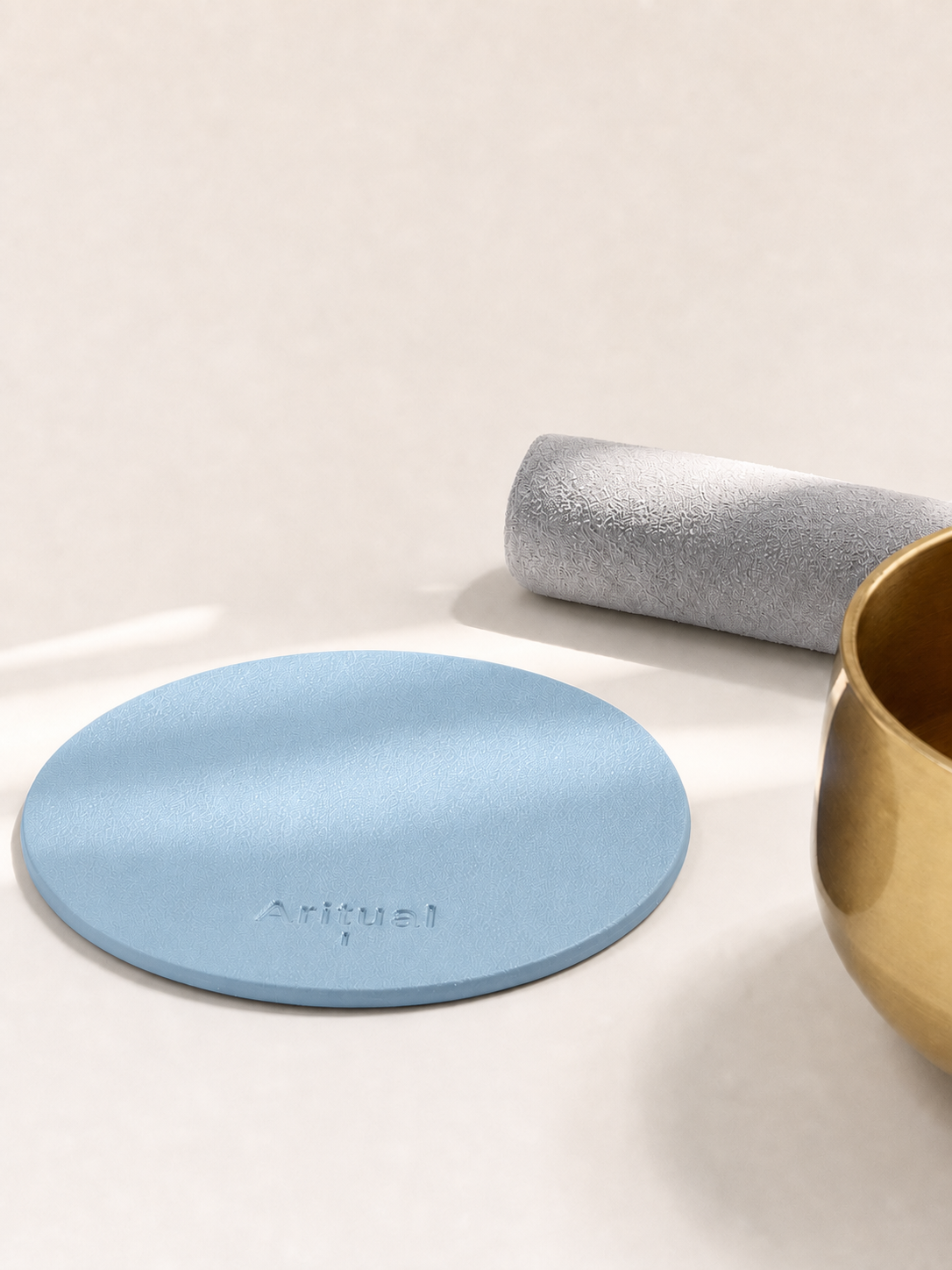 Powder blue leather pad beside the brass singing bowl and suede mallet