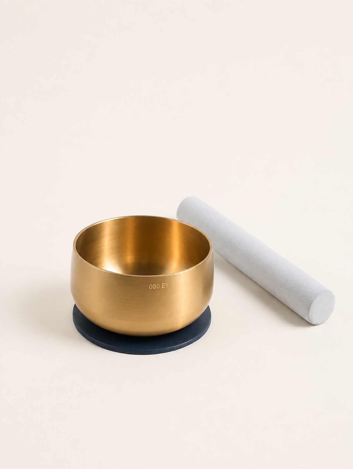 Engraved brass bowl seated on the navy blue pad with the mallet alongside