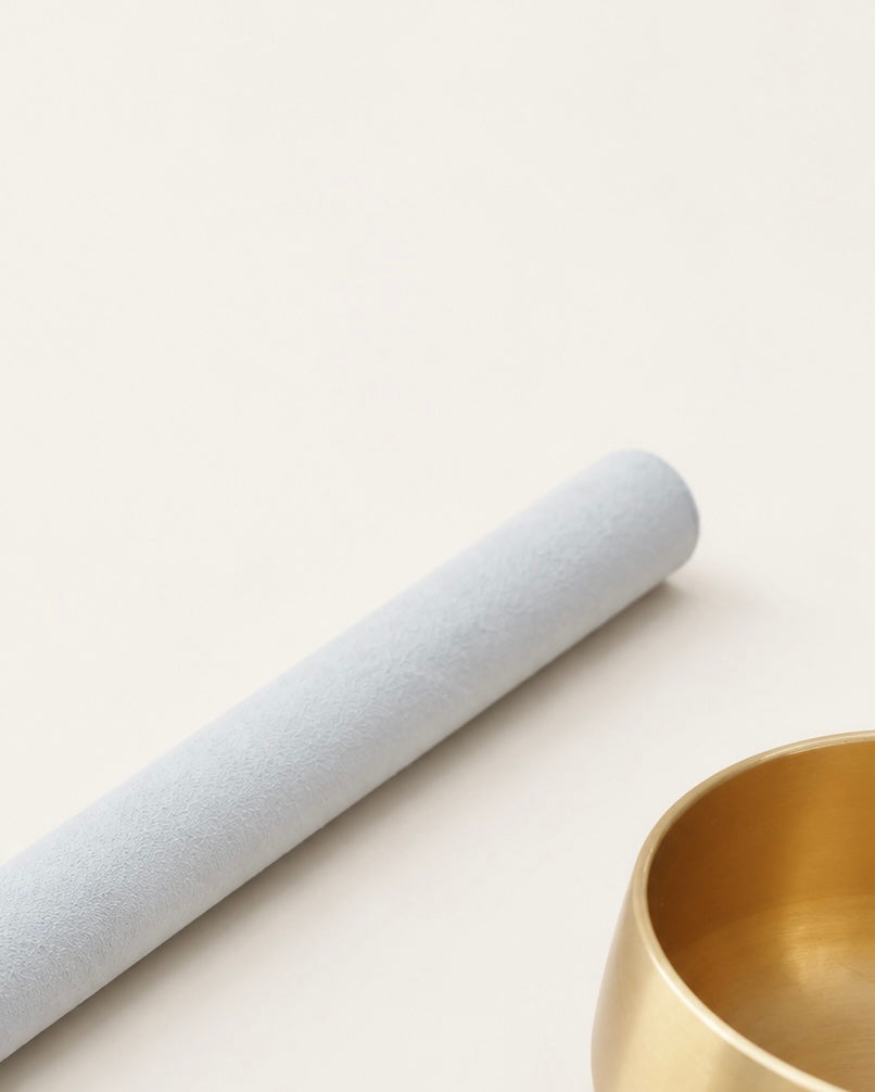 Pale suede mallet resting beside the brass singing bowl