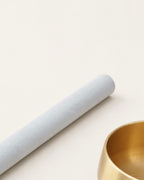 Pale suede mallet resting beside the brass singing bowl